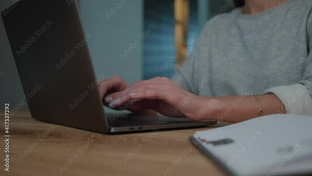 A close-up view of a woman is typing on keyboard in her laptop while sitting at the apartments A close-up view of a woman is typing on keyboard in her laptop while sitting at the apartments