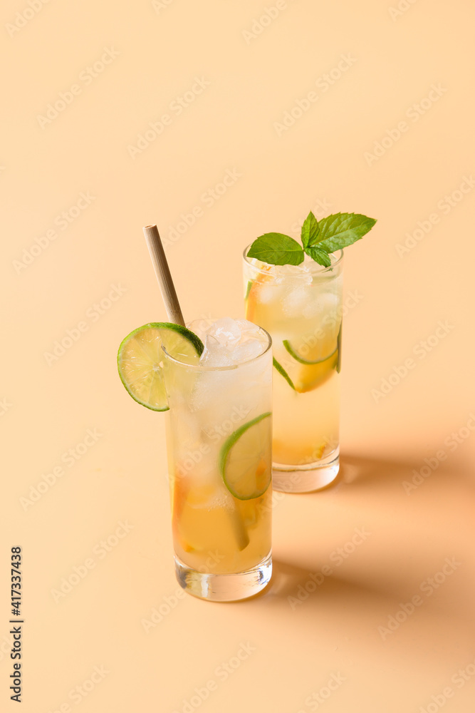 Fototapeta premium Refreshing orange two lemonade sodas with lime slice on color background. Summer fresh drink.