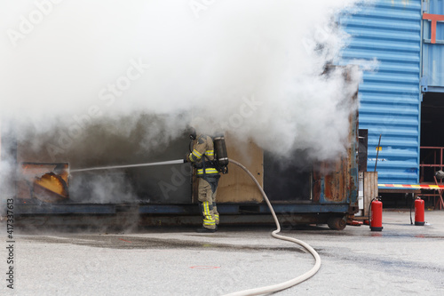 Firefighter holding hose and spraying water