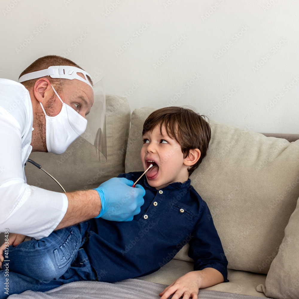 Doctor testing child for the coronavirus at home. Boy having a test swab taken by male doctor at home. COVID-19 home test kit. Specialist holding cotton swab and test tube ready to collect DNA. Doctor testing child for the coronavirus at home. Boy having a test swab taken by male doctor at home. COVID-19 home test kit. Specialist holding cotton swab and test tube ready to collect DNA.