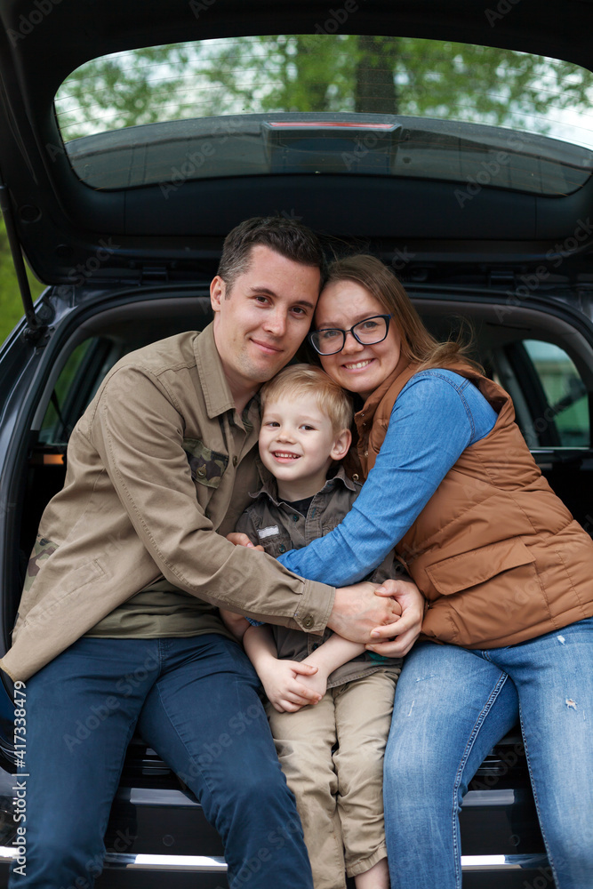 Family sitting in open trunk of their car Family sitting in open trunk of their car