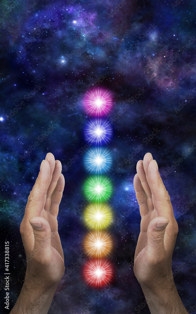 Sending Distant Healing to the Seven Chakras - male parallel hands with a neat stack of seven rainbow coloured chakra vortexes between against a dark deep space background with copy space
