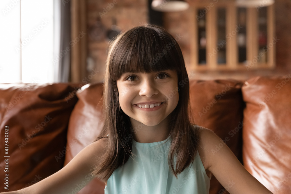 Close up headshot portrait of happy small 8s Latino girl child have webcam online talk on gadget at home. Smiling little Hispanic kid look at camera speak on video call. Virtual event concept. Close up headshot portrait of happy small 8s Latino girl child have webcam online talk on gadget at home. Smiling little Hispanic kid look at camera speak on video call. Virtual event concept.