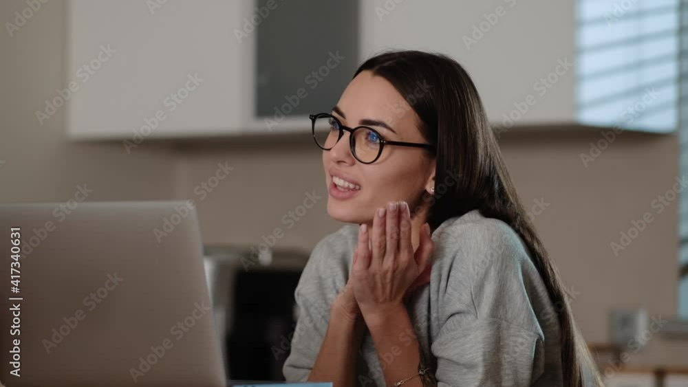 A smiling woman is talking with video connection using her laptop sitting inside the apartments A smiling woman is talking with video connection using her laptop sitting inside the apartments