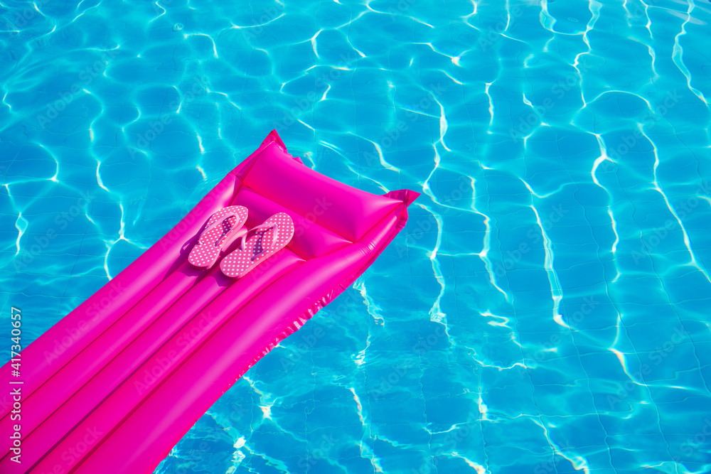 Beach summer holiday background. Inflatable air mattress, flip flops on swimming pool.