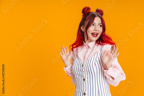 Pleased girl with red hair looking aside with hands up