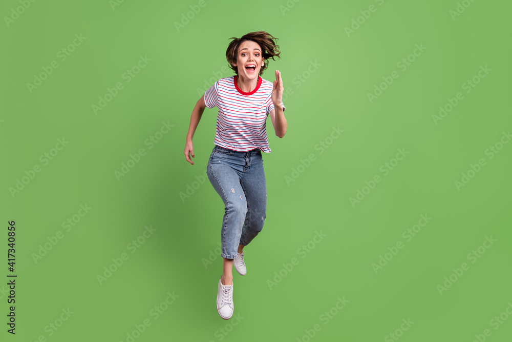 Full length body size view of pretty cheerful girl jumping running movement isolated over green pastel color background Full length body size view of pretty cheerful girl jumping running movement isolated over green pastel color background