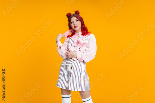 Thinking girl with red hair posing with stuffed diary and feather