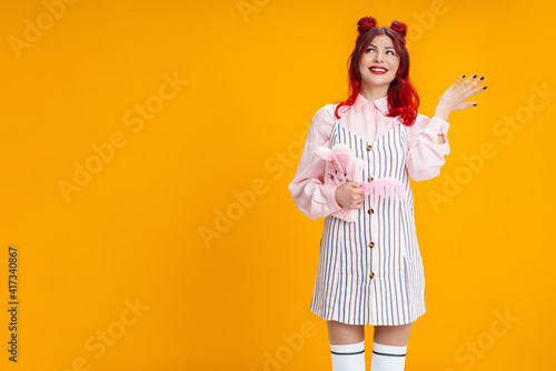 Joyful girl gesturing while posing with stuffed diary and feather