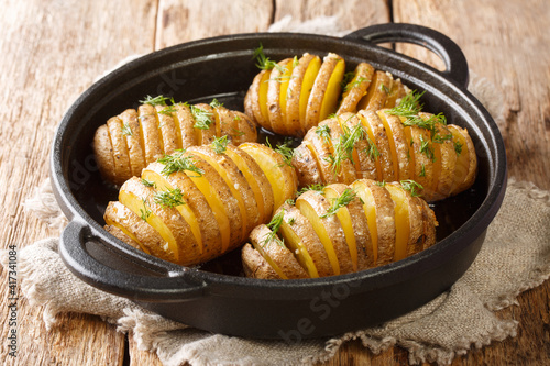 Classic recipe Hasselback potatoes close-up on a frying pan on the table. Horizontal
