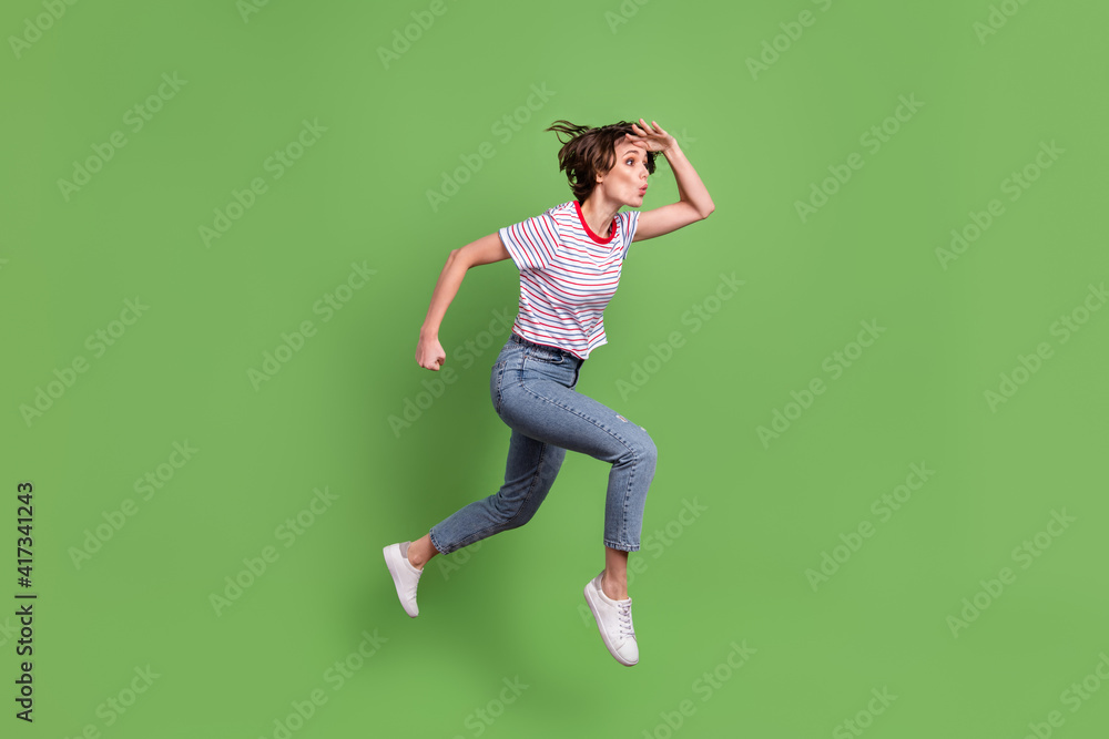 Full length body size profile side view of attractive amazed girl jumping running find pout lips isolated over green pastel color background Full length body size profile side view of attractive amazed girl jumping running find pout lips isolated over green pastel color background