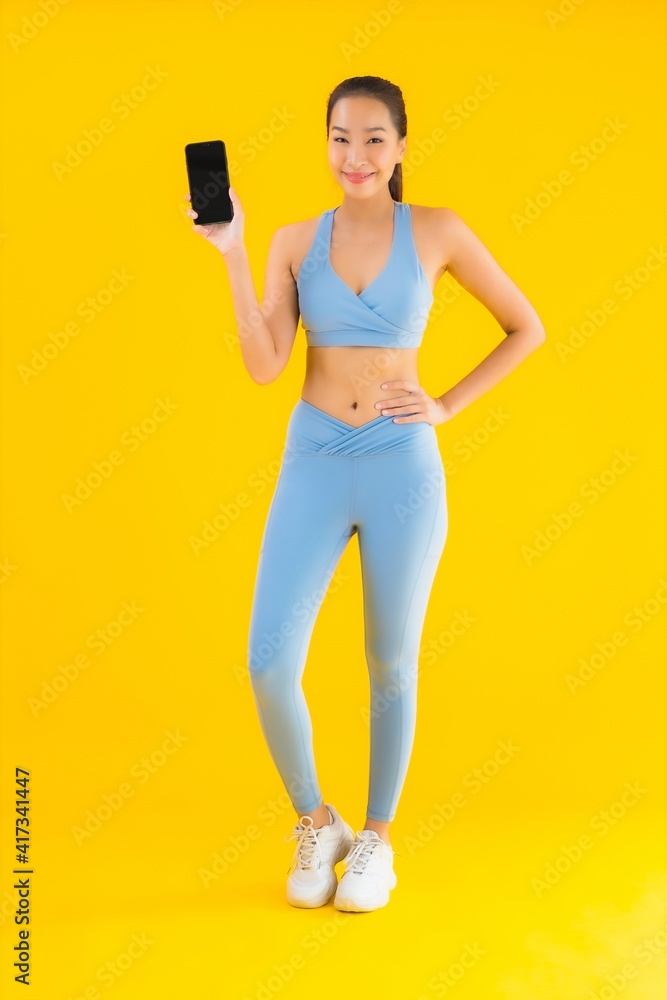 Portrait beautiful young asian woman with smart mobile phone on yellow isolated Portrait beautiful young asian woman with smart mobile phone on yellow isolated