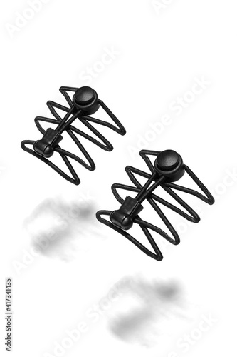 Subject shot of black no tie shoelaces with catch locks and tie ends clips. Elastic shoelaces with locking system are hanging in the air on the white background. 