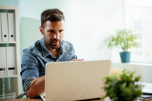 Young businessman working on laptop and drinking coffee in his office. Businessman on coffee break