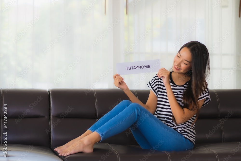 Portrait beautiful young show paper stay home on sofa in livingroom for save people from coronavirus Portrait beautiful young show paper stay home on sofa in livingroom for save people from coronavirus