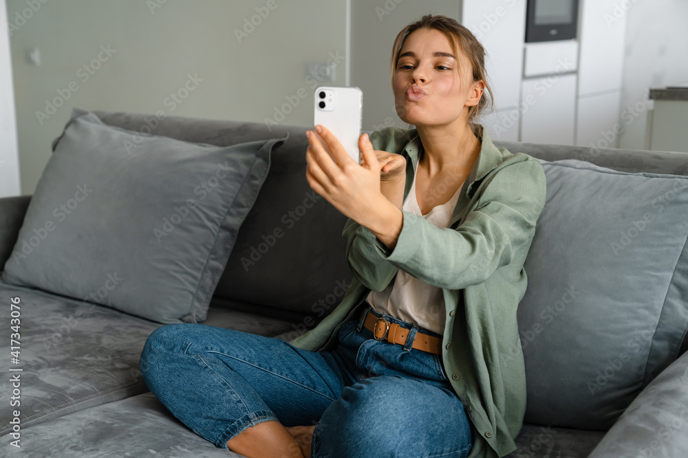 Happy nice woman sending air kiss while taking selfie on mobile phone Happy nice woman sending air kiss while taking selfie on mobile phone