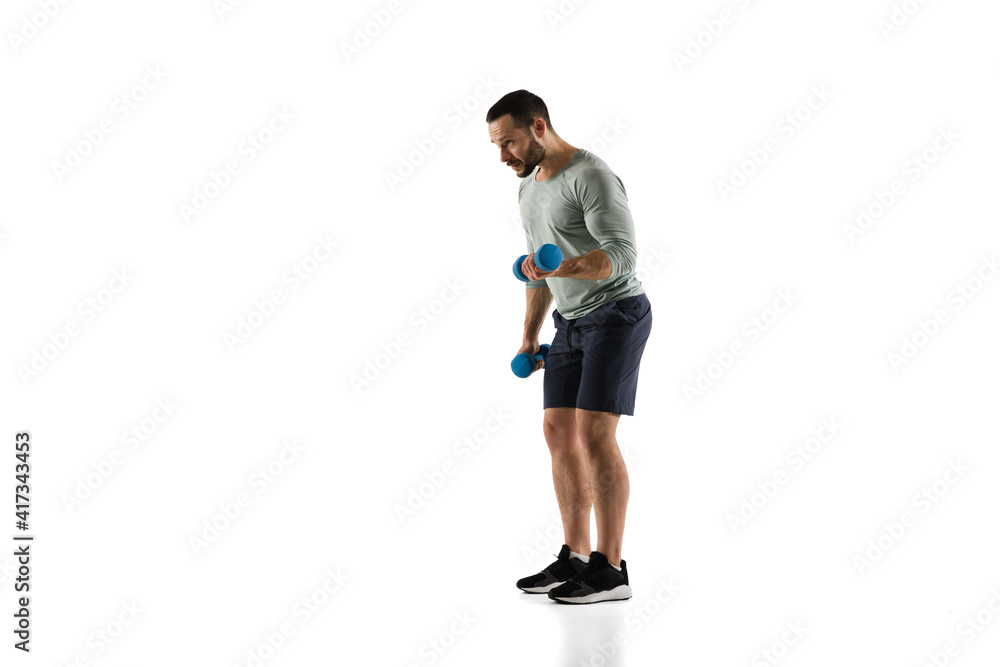 Dumbbells. Young caucasian male model in action, motion on white background with copyspace. Concept of sport, movement, energy and dynamic, healthy lifestyle. Training, practicing. Authentic. Dumbbells. Young caucasian male model in action, motion on white background with copyspace. Concept of sport, movement, energy and dynamic, healthy lifestyle. Training, practicing. Authentic.