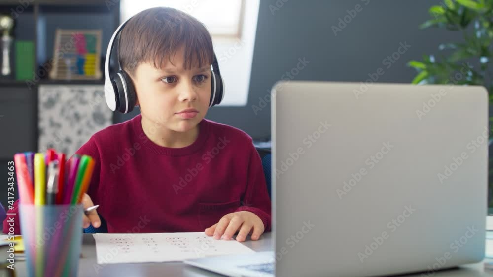 Handheld video of boy with headphones during remote learning at home. Shot with RED helium camera in 8K. Handheld video of boy with headphones during remote learning at home. Shot with RED helium camera in 8K.