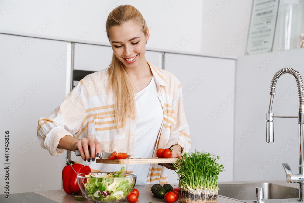 Joyful blonde woman smiling while preparing fresh salad Joyful blonde woman smiling while preparing fresh salad