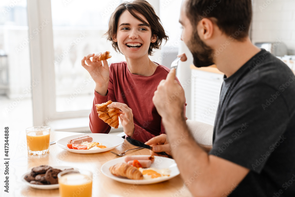 Cheerful attractive young couple having tasty breakfast