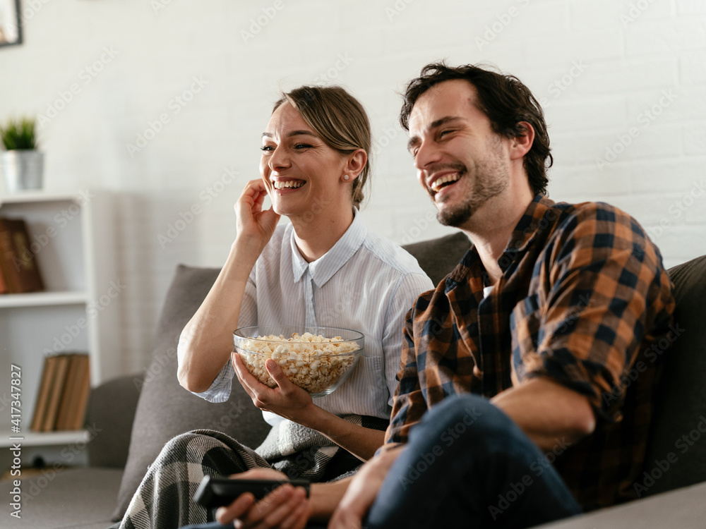 Young loving couple relaxing on sofa together. Happy couple watching movie at home Young loving couple relaxing on sofa together. Happy couple watching movie at home