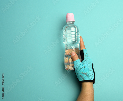 transparent plastic bottle with fresh water in a female hand on a blue background