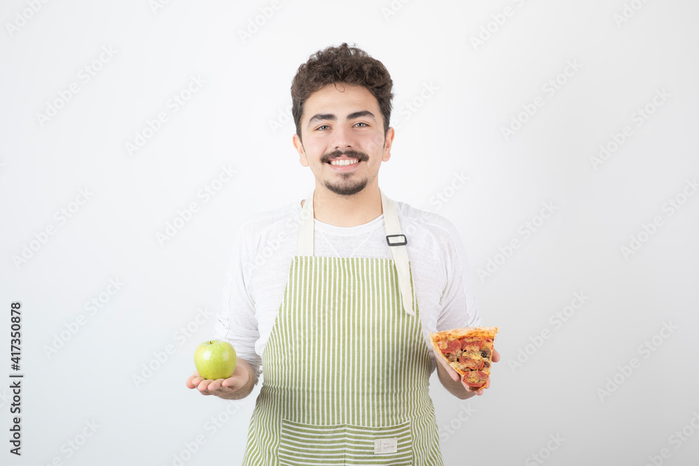 Portrait of smiling male cook showing pizza and green apple on white background Portrait of smiling male cook showing pizza and green apple on white background