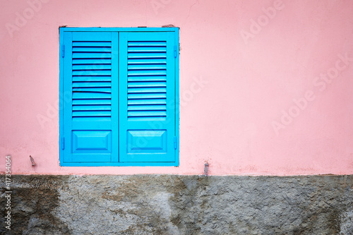 Pink wall with blue window shutter
