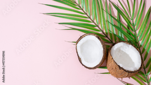 Coconut halves with palm leaves on pink background. Organic cosmetics, food, summertime sale banner. Copy space for text or product place