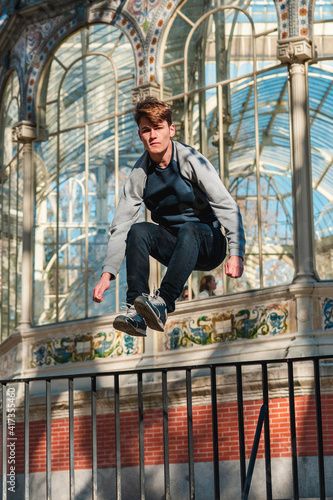 Chico caucásico joven haciendo parkour y acrobacias en el palacio de cirstal de Madrid (RETIRO) photo