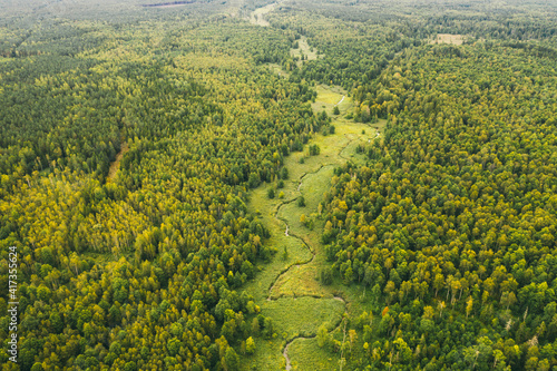 Top view of the valley of a meandering river among green fields and forests