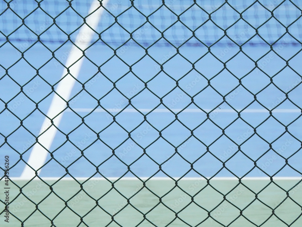 green wire mesh of fence enclose the tennis court green wire mesh of fence enclose the tennis court
