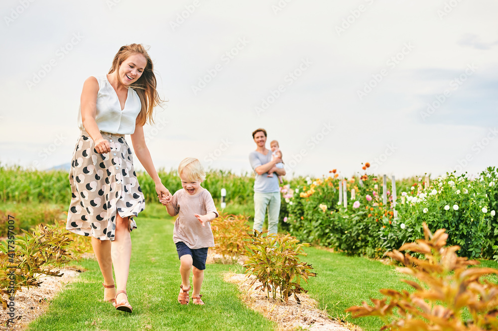 Happy young family with baby girl and toddler boy playing together on flower farm Happy young family with baby girl and toddler boy playing together on flower farm