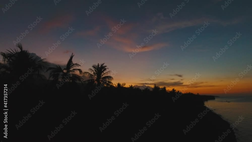 Sunset, silhouette of palm trees. Aerial view of sunset on the ocean coast, mountains, sea, beach, sky, clouds Bali, Indonesia Aerial footage Sunset, silhouette of palm trees. Aerial view of sunset on the ocean coast, mountains, sea, beach, sky, clouds Bali, Indonesia Aerial footage