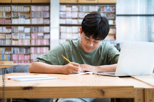 Young collage student using computer and mobile device studying online.