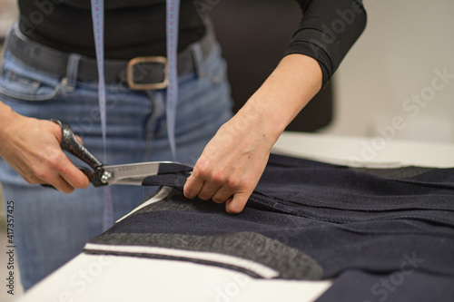 Dressmaker cutting dress fabric on sketch line. Fashion designer tailor or sewer in workshop studio designing new collection clothes. Business owner shop and entrepreneur concept