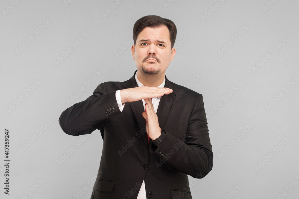 man needs more time. Working without productivity, the business falls. indoor studio shot. isolated on gray background. handsome businessman with black suit, red tie and mustache looking at camera. man needs more time. Working without productivity, the business falls. indoor studio shot. isolated on gray background. handsome businessman with black suit, red tie and mustache looking at camera.