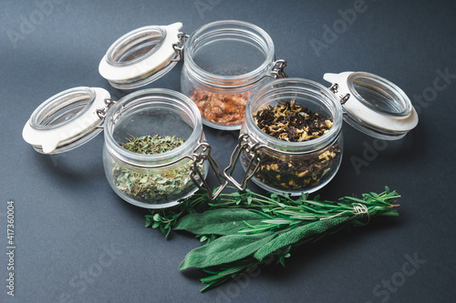 Different varieties traditional black, red and green tea in glass jar and on a metal spoon on gray background