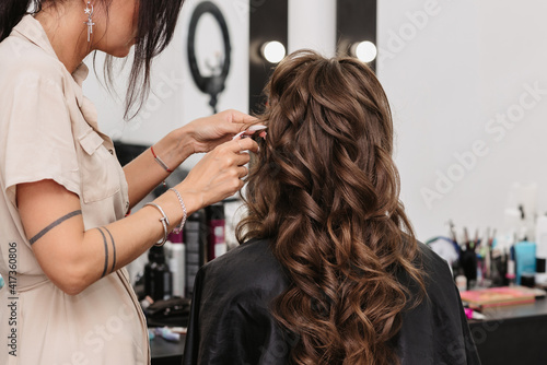 bride with brown curly long hair in a beauty salon is preparing for the wedding day