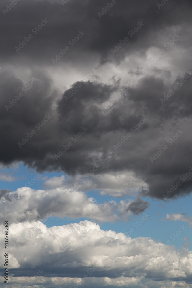Storm sky. Dark grey and white big cumulus clouds against blue sky background, cloud texture, thunderstorm Storm sky. Dark grey and white big cumulus clouds against blue sky background, cloud texture, thunderstorm