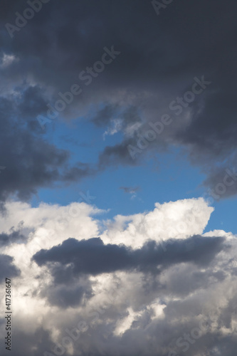 Thunderstorm clouds texture. Storm sky with dark grey and white cumulus clouds against blue sky background