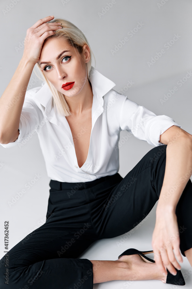 Fashion portrait of sensual trendy woman posing sitting on floor on white studio background Fashion portrait of sensual trendy woman posing sitting on floor on white studio background