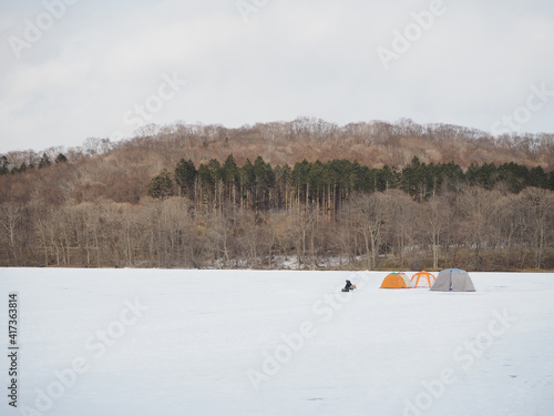 北海道の凍ったポロト湖でワカサギを釣る人