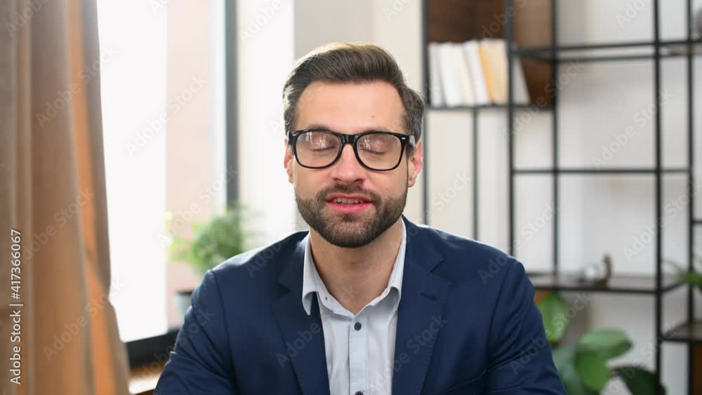 Young bearded businessman in formal clothes sitting at desk, talking at camera, introducing himself on online job interview, smart man presenting the idea during business video call. Webcam view Young bearded businessman in formal clothes sitting at desk, talking at camera, introducing himself on online job interview, smart man presenting the idea during business video call. Webcam view