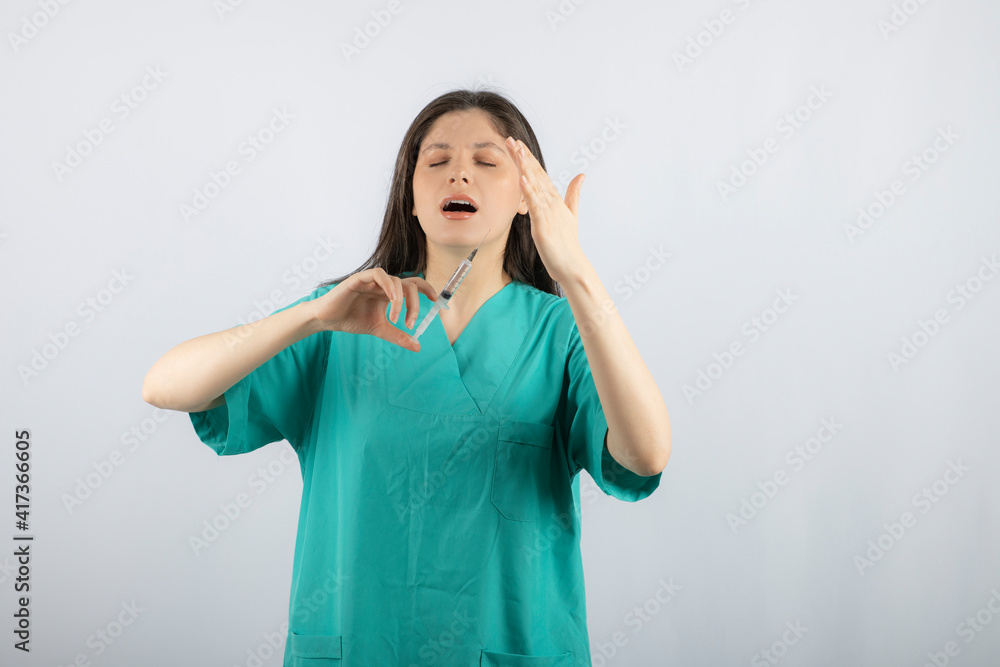 Portrait of female doctor holding a large syringe. Portrait of female doctor holding a large syringe.
