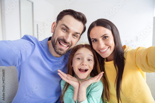 Photo of young happy family small girl mother father take selfie together smile good mood inside home living-room