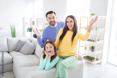 Photo of cheerful family mom dad kid happy positive smile have fun wave hand hello hi sit sofa home together
