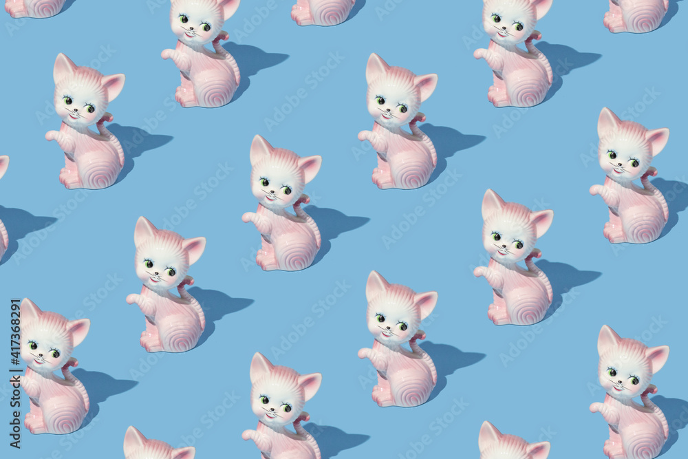 Creative pattern made with pastel pink cat or kitten vintage figurine on pastel blue background. Retro aesthetic idea. Romantic, fun and happy concept.