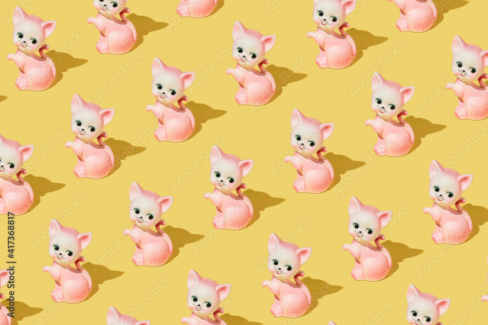 Creative pattern made with pastel pink cat or kitten vintage figurine on bright yellow background. Retro aesthetic idea. Romantic colorful concept. Creative pattern made with pastel pink cat or kitten vintage figurine on bright yellow background. Retro aesthetic idea. Romantic colorful concept.