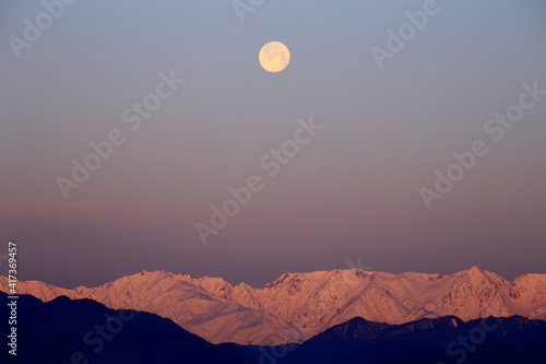 沈む月と朝日に照らされる雪山